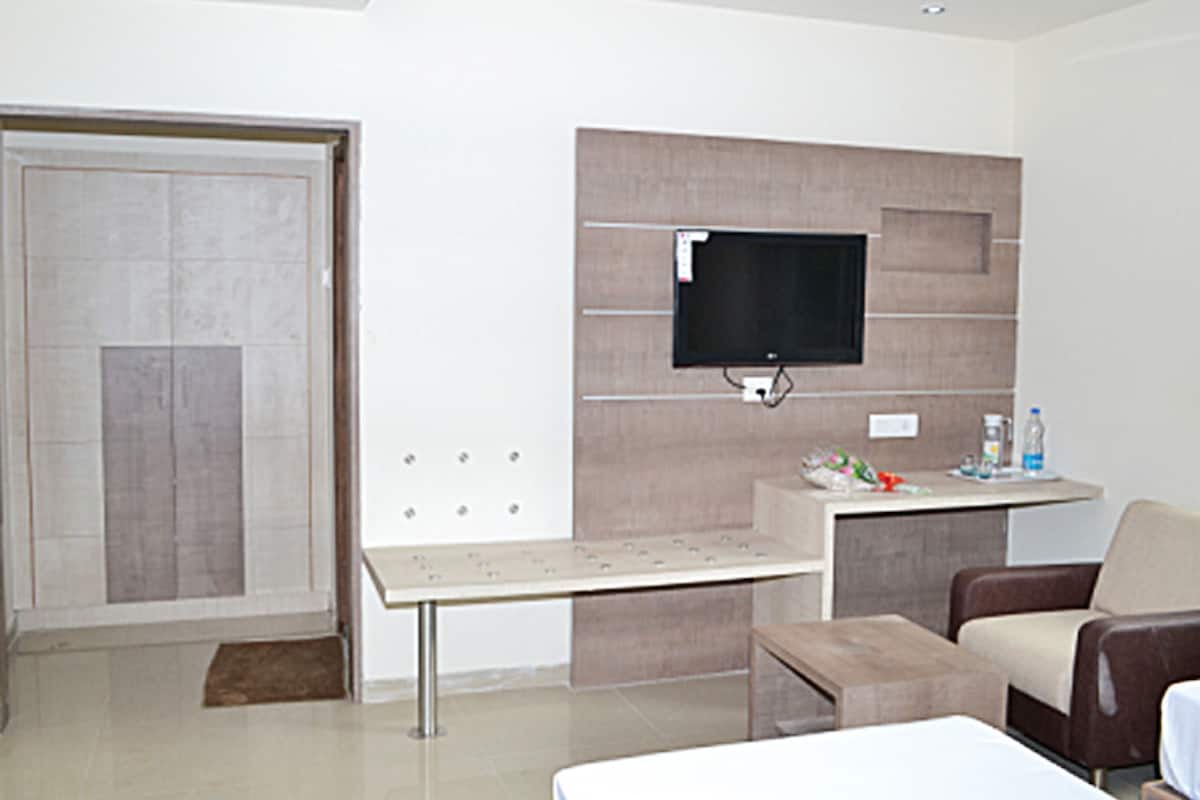Un salon moderne avec un téléviseur à écran plat fixé au mur, une petite table, un canapé et une porte.