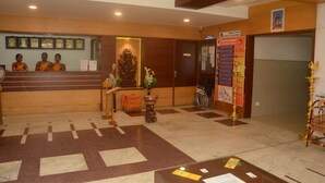 A reception area with a counter, framed pictures, a statue, a wheelchair, and informational posters.