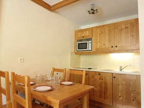 Una cucina compatta con mobili in legno, un forno a microonde e un tavolo da pranzo per quattro persone.