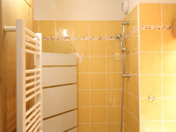 A shower with yellow tiles and a white towel rack.
