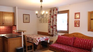 A compact living space with a kitchenette, a dining table, a sofa, and a small table. - Spacious apartment in Lanslevillard with balcony and parking (Lanslevillard)