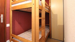 A bunk bed room with a wooden door and red walls. - Val Cenis Le Haut: Cozy Studio for 3 near Slopes & Amenities, Ski Locker Included (Lanslevillard)