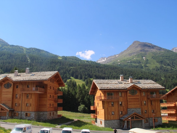 Un edificio de estilo chalet de madera con balcones, con montañas al fondo.
