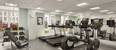 Une salle de sport équipée de tapis de course, de vélos elliptiques et de matériel de musculation.