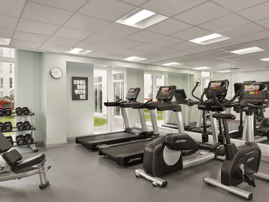 Una palestra con tapis roulant, ellittiche e attrezzature per sollevamento pesi.