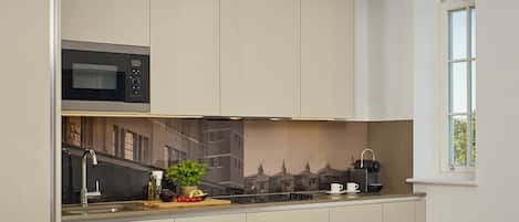 A modern kitchen with a built-in microwave, a sink, and a window with a view of buildings.