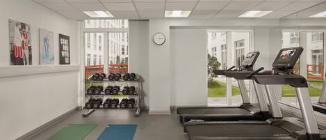A gym with treadmills, dumbbells, and exercise mats.