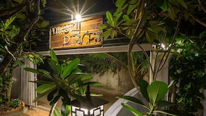A sign for 'Honesty Place' with a wooden design and a metal frame, surrounded by lush greenery and a small decorative lantern. - Homestay Songngu Pisces (Can Tho)