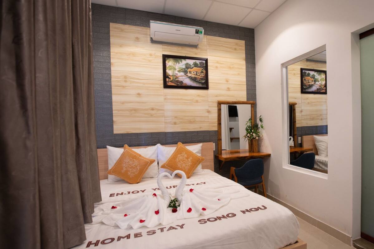 A hotel room with a bed, a desk, a chair, a mirror, and a picture on the wall.