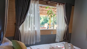 A room with a bed, curtains, and a view of an outdoor area with chairs and a table. - Homestay Songngu Pisces (Can Tho)