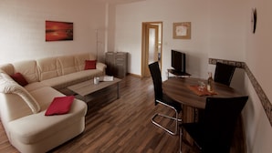 Ein modernes Wohnzimmer mit einer Couch, einem Couchtisch, einem Fernseher und einem Essbereich.