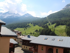A mountain village with traditional buildings, a clear view of the surrounding hills and mountains, and a small parking area in the foreground. - Apartment in Lanslebourg Village, Val Cenis - 300m from Ski Slopes (Lanslebourg-Mont-Cenis)
