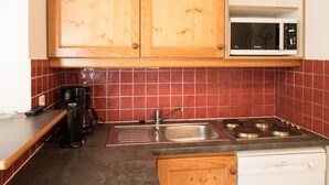 A kitchen with wooden cabinets, a microwave, a sink, and a coffee maker. - Spacious apartment for 6, south balcony, parking (Lanslevillard)