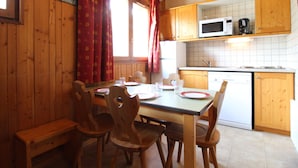 A wooden interior with a dining table set for four, a microwave, and a sink.