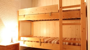 A bunk bed with a wooden frame and a small table beside it.