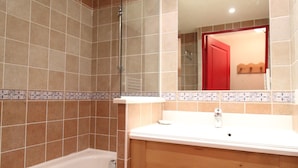 Ein Badezimmer mit einer Badewanne, einem Holzwaschtisch und einem Spiegel.