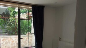Un dormitorio con una cama grande, una ventana con vista a un jardín y un ventilador de techo.