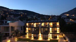 Una casa moderna de dos pisos con piscina, rodeada por un patio bien iluminado y vistas a la colina.