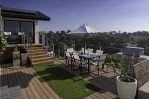 Eine Terrasse mit Esstisch und Stühlen, einem Grill und einem Blumentopf.