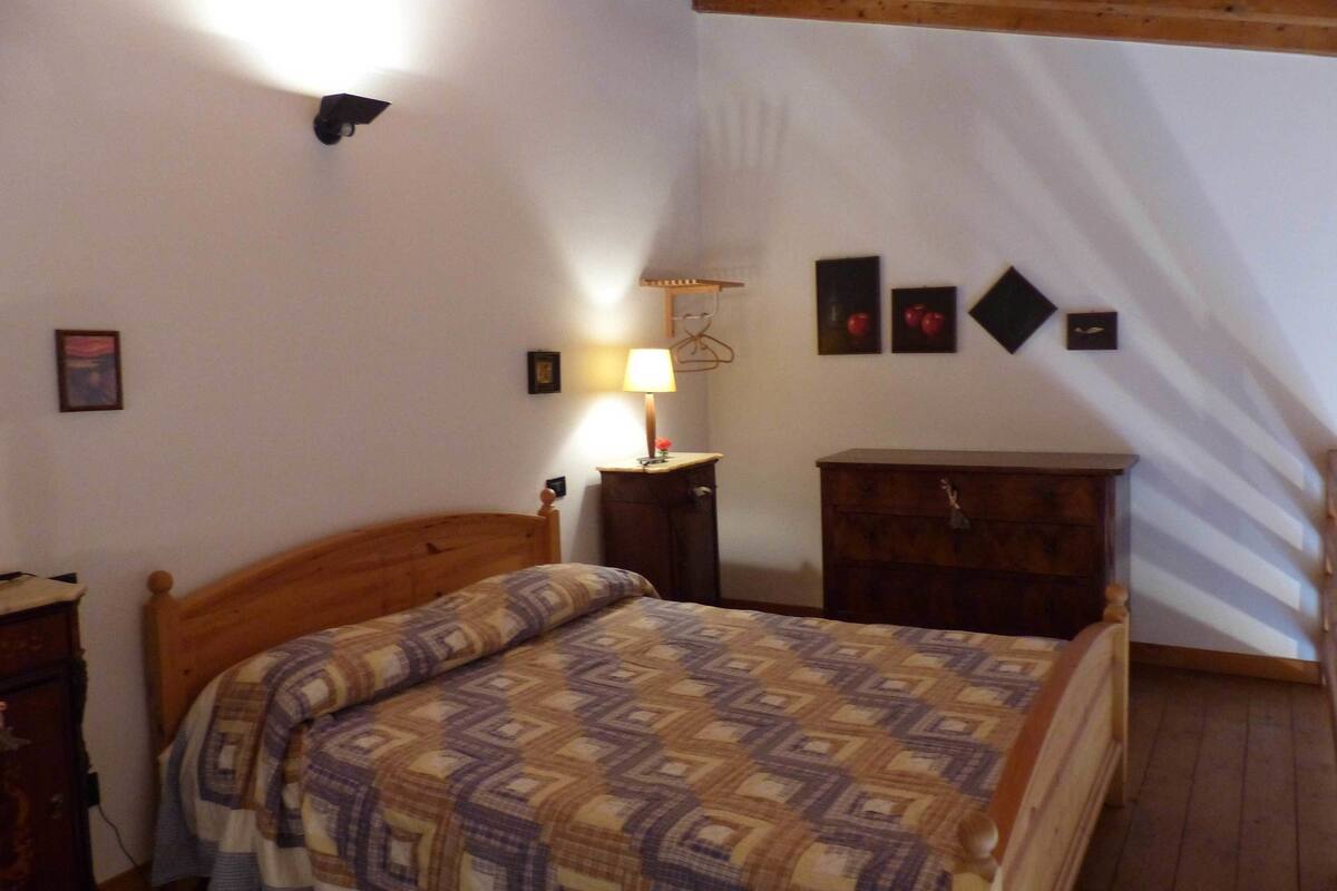 A bedroom with a wooden bed, a bedside table, a dresser, and wall-mounted lamps.