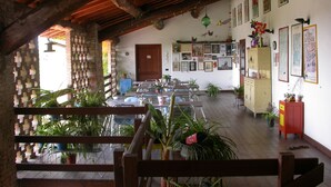 Un espace repas avec des tables et des chaises en bois, des plantes en pot et un mur en briques.