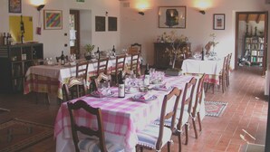 Un espace repas avec des tables dressées pour le repas, des chaises et une variété d’articles de table, notamment des verres à vin et des bouteilles.