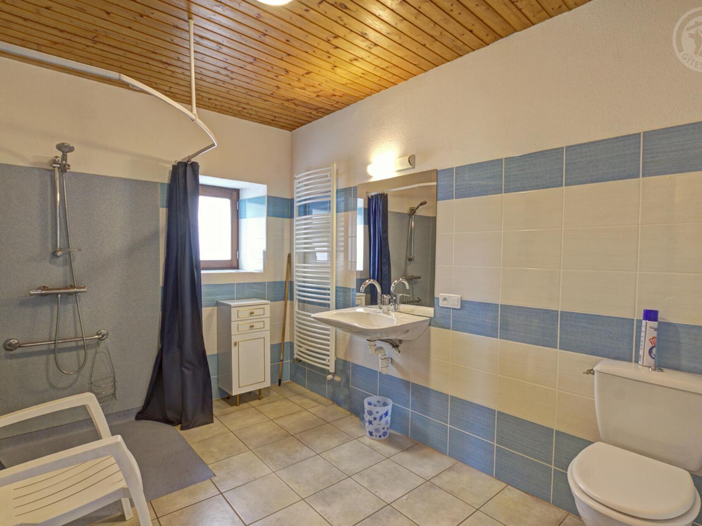 Une salle de bain avec une douche, un lavabo, des toilettes et une fenêtre.
