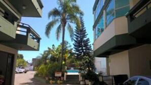 Un edificio de estilo arquitectónico moderno, con un patio central que incluye una palmera y otra vegetación. Se observan varios pisos, y el edificio tiene techo plano.