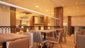 A modern restaurant interior with wooden tables and chairs, a glass partition, and a decorative hanging light fixture. - Forte Express (Macapa)