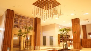 A modern lobby with wooden paneling, a glass reception desk, and hanging light fixtures. - Forte Express (Macapa)