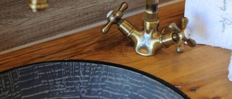 A vintage brass faucet with multiple handles, a wooden frame, and a black ceramic sink.