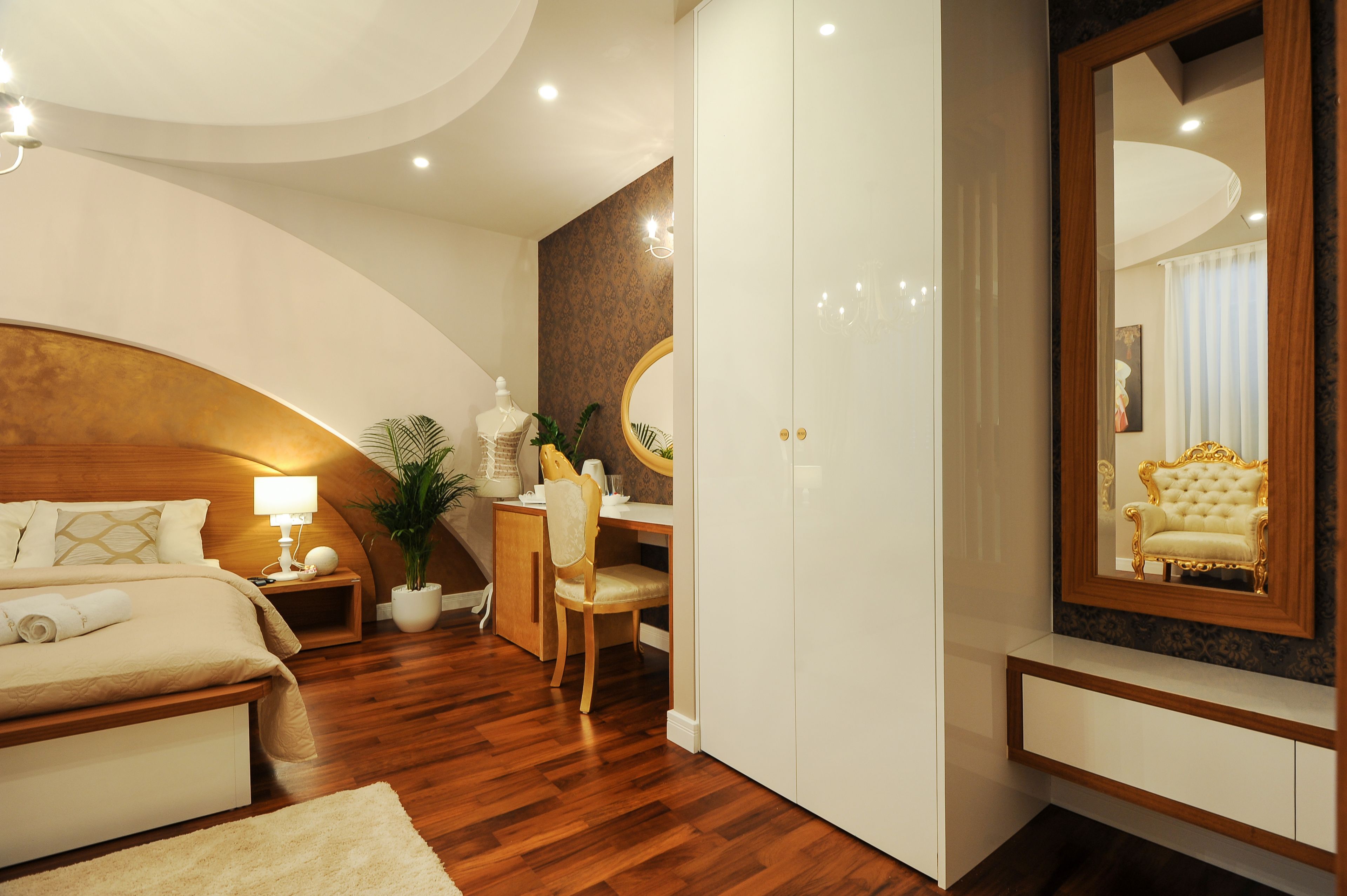 A modern bedroom with a wooden headboard, a desk, and a large mirror.