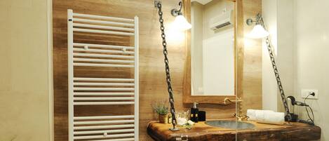 Un baño moderno con tocador de madera, toallero, espejo y zona de ducha.