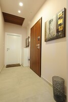 A hallway with a wooden door, a white refrigerator, and a wall-mounted artwork.