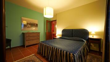A bedroom with a bed, a dresser, a chair, a rug, and a painting on the wall.