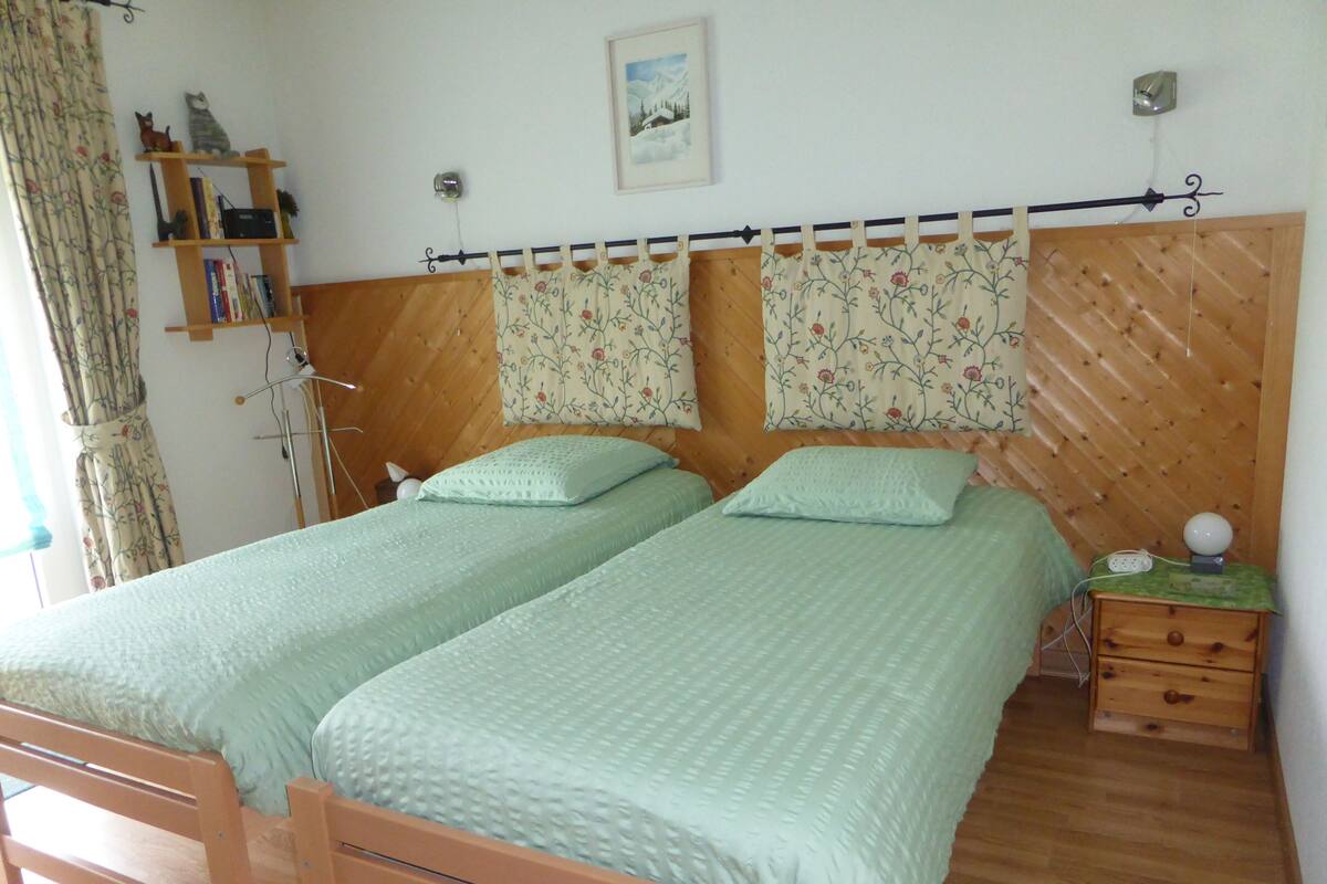 A double bed with a wooden headboard and a nightstand with a lamp.