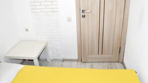 A room with a wooden door, a white bench, and a yellow bedspread. - Hostel Train Station (Kyiv)
