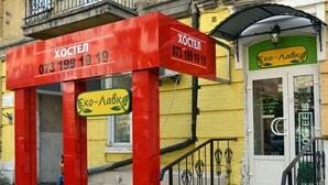 A building with a red and yellow facade, a staircase leading to the entrance, and a sign with a phone number. - Hostel Train Station (Kyiv)