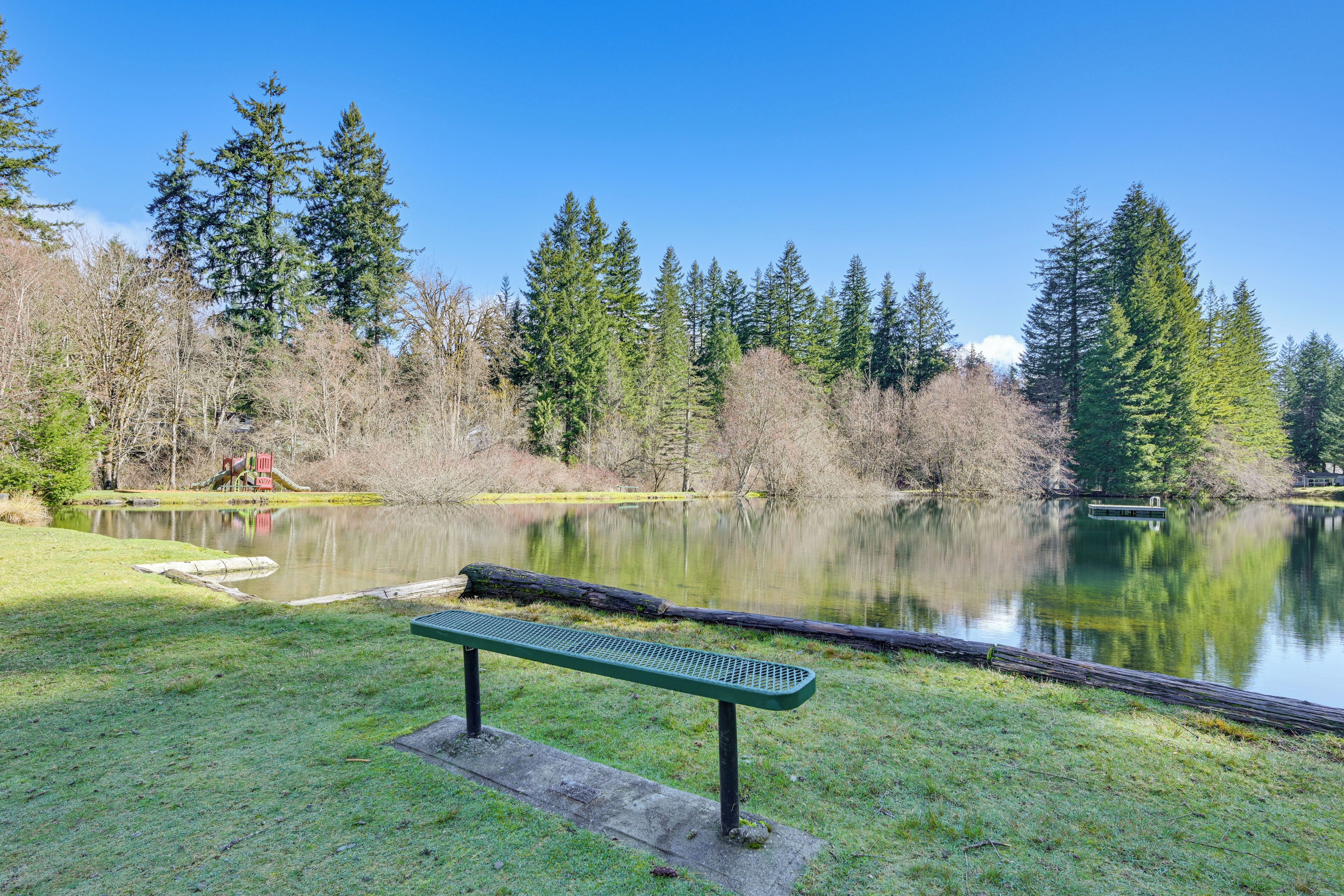 A park with a bench, a lake, and trees.