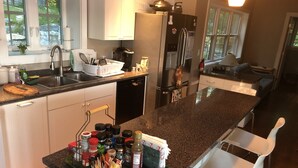 A modern kitchen with granite countertops, stainless steel appliances, and white cabinetry. - Ocean-Beach Front Cottage on Blue Hill Bay w/ Mt Desert Island on the Horizon... (Surry)