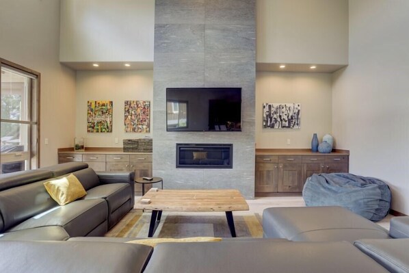 A modern living room with a fireplace, a sofa, a coffee table, and artwork on the walls. - Kangaroo Loop - Closest to Bachelor! 5BR/3.5BA, Jacuzzi (Bend)