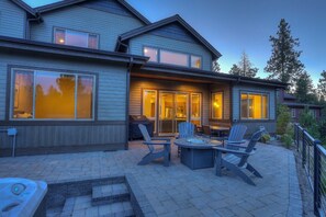 A two-story house with a patio area featuring outdoor furniture and a hot tub.
