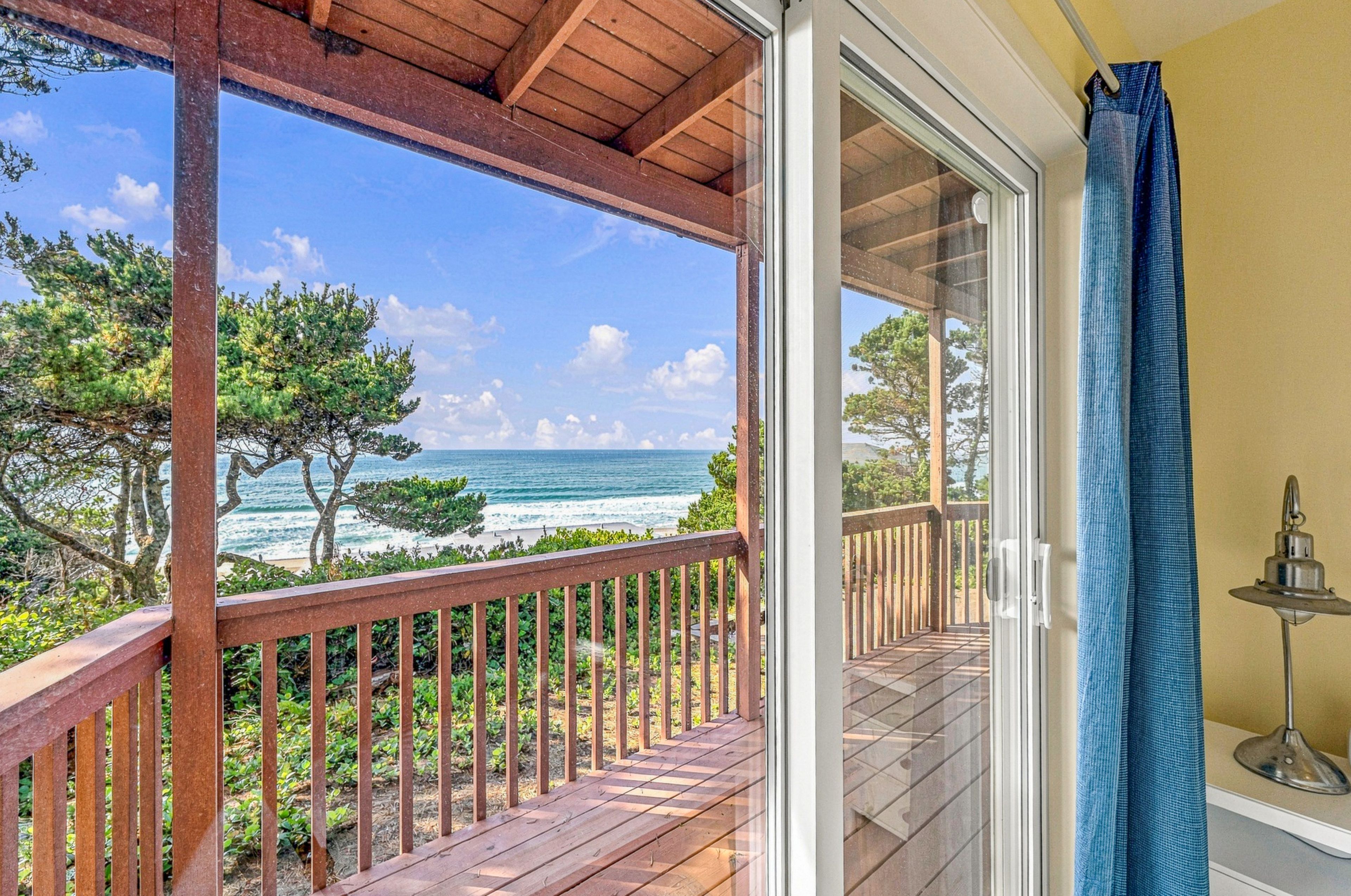 A wooden balcony with a view of the ocean and trees.