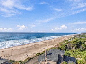 A coastal property with a beach view, a paved pathway, and a house with a sloped roof. - Breaking Waves Ocean View Retreat (Depoe Bay)