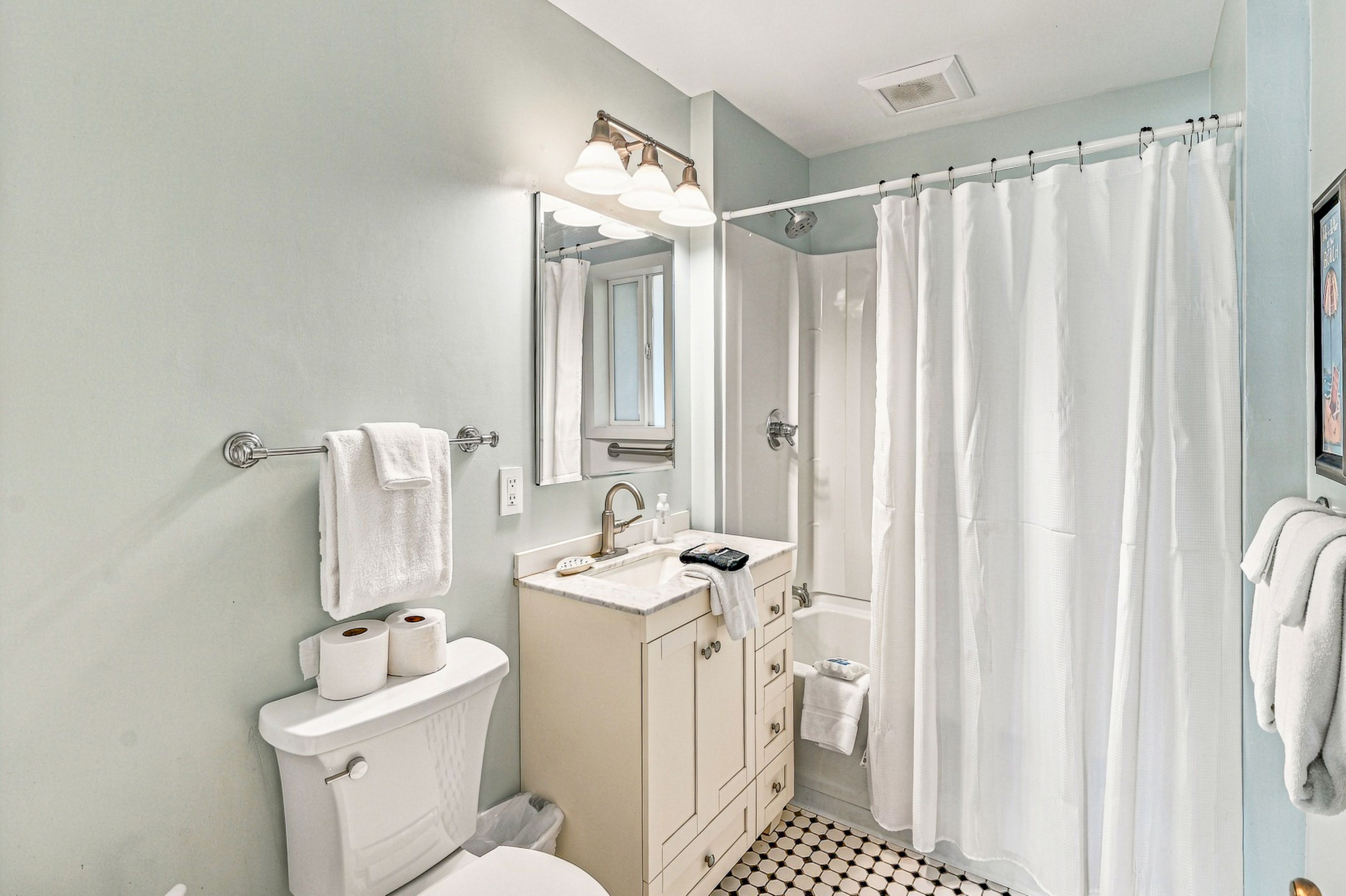 A bathroom with a toilet, sink, mirror, and shower curtain.