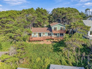 Ein zweistöckiges Haus mit Balkon, umgeben von dichtem Wald.