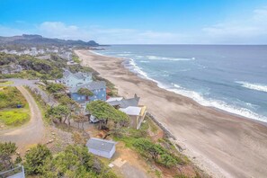 A coastal residential area with houses along the beach, a clear sky, and a view of the ocean.