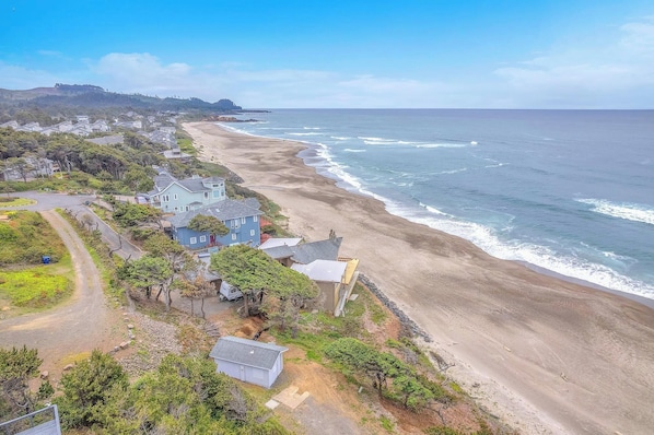 A coastal residential area with houses along the beach, a clear sky, and a view of the ocean.