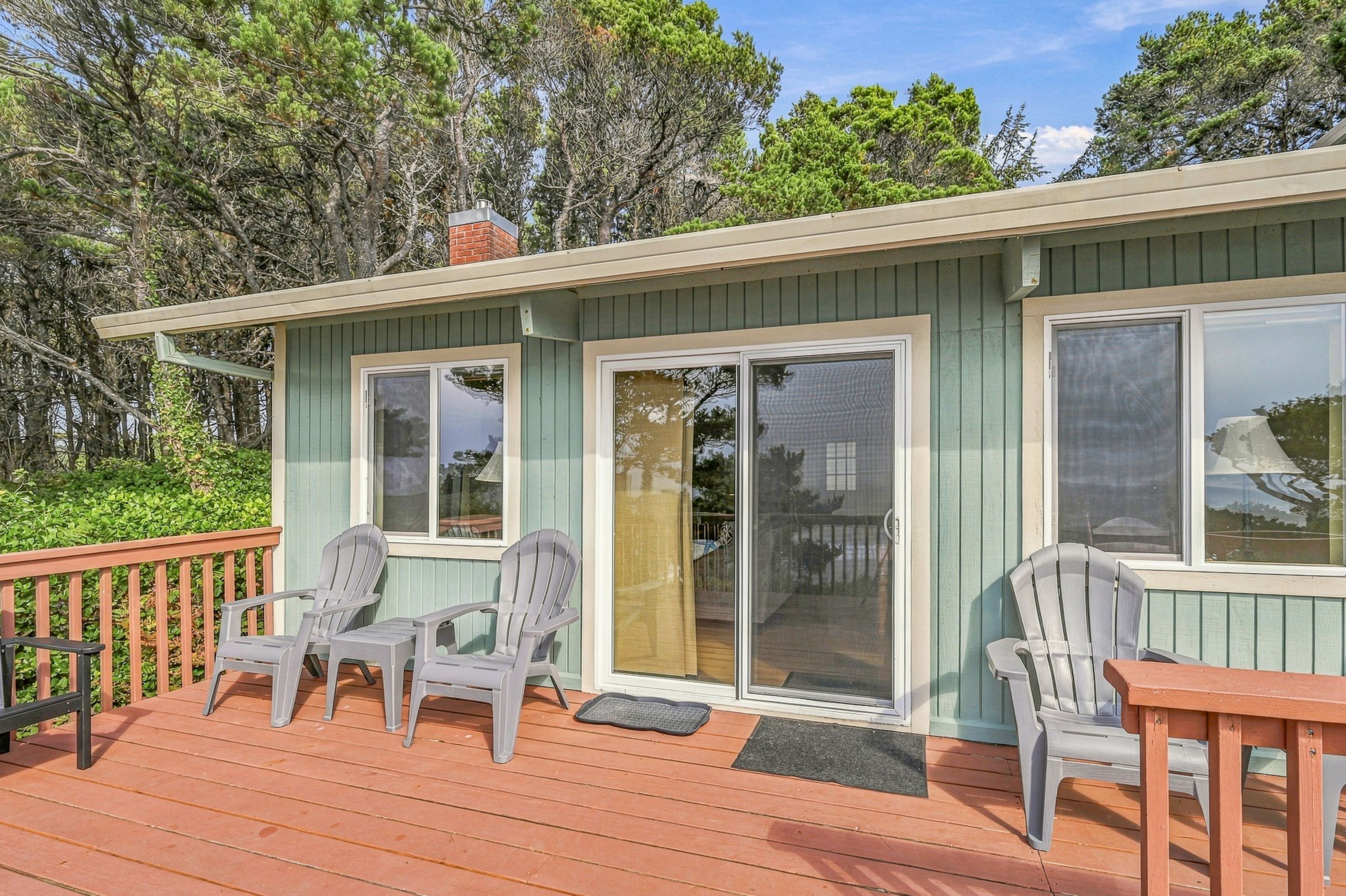 Une petite maison dotée d’une terrasse, de deux portes-fenêtres coulissantes et de deux fauteuils Adirondack.