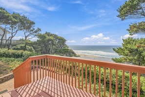 A wooden deck with a view of the beach and ocean.
